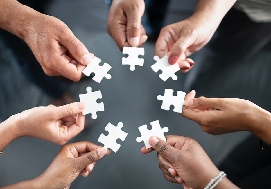 Closeup shot of a group of unrecognisable businesspeople holding puzzle pieces together